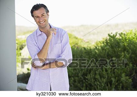 Portrait of a mid adult man standing with his hand on his chin and smiling View Large Photo Image Stock Image - Portrait of a mid adult man standing with his hand on his chin and smiling. Fotosearch