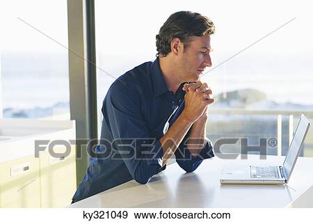 Side profile of a mid adult man looking at a laptop View Large Photo Image Stock Photo - Side profile of a mid adult man looking at a laptop. Fotosearch