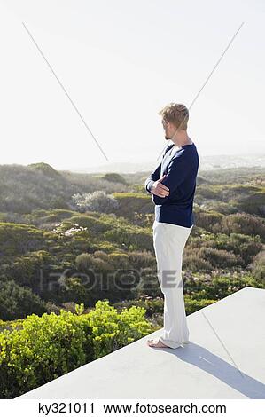 Young man looking at view from the terrace of a house View Large Photo Image Stock Image - Young man looking at view from the terrace of a house. Fotosearch