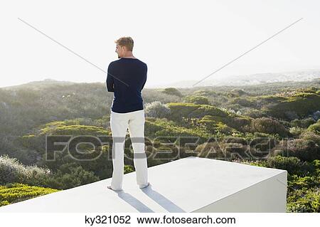 Young man looking at view from the terrace of a house View Large Photo Image Stock Image - Young man looking at view from the terrace of a house. Fotosearch