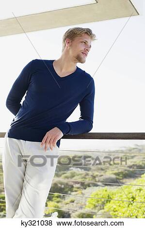 Young man standing at a balcony View Large Photo Image Stock Photo - Young man standing at a balcony. Fotosearch