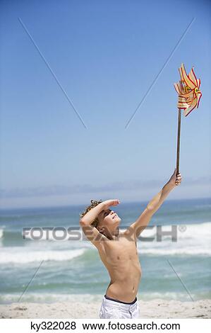 Boy holding a pinwheel on the beach View Large Photo Image Stock Photo - Boy holding a pinwheel on the beach. Fotosearch