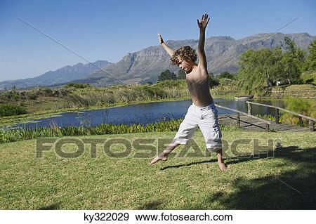 Stock Photo - Cute little boy doing cartwheel against mountain. Fotosearch