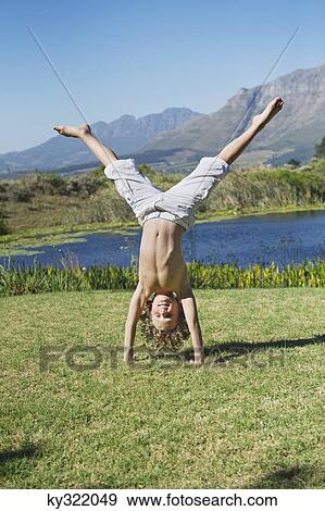 Stock Photo - Cute little boy doing cartwheel against mountain. Fotosearch