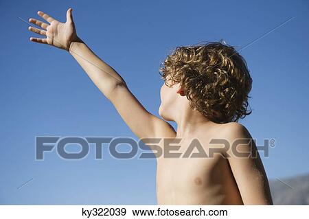 Cute little boy raising his hand against clear sky View Large Photo Image Stock Photo - Cute little boy raising his hand against clear sky. Fotosearch