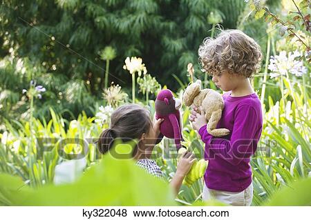 Stock Photo - Cute little boy standing with little girl in a garden. Fotosearch