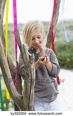 Girl leaning against a tree and eating fruit View Large Photo Image Stock Photography - Girl leaning against a tree and eating fruit. Fotosearch