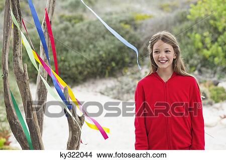 Girl standing near a tree and smiling View Large Photo Image Picture - Girl standing near a tree and smiling. Fotosearch