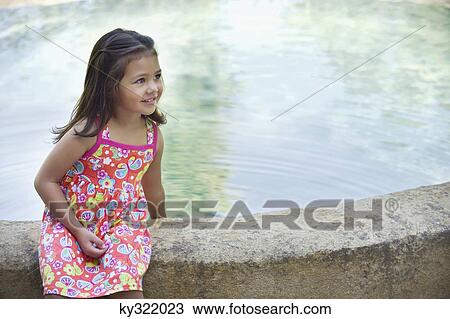 Stock Image - Little girl sitting by the swimming pool. Fotosearch