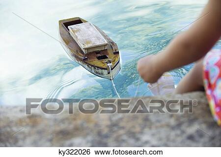 Low section view of a girl sitting at edge of swimming pool with toy boat in water View Large Photo Image Stock Photograph - Low section view of a girl sitting at edge of swimming pool with toy boat in water. Fotosearch