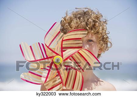 Portrait of a boy holding a pinwheel in front of his face View Large Photo Image Stock Image - Portrait of a boy holding a pinwheel in front of his face. Fotosearch