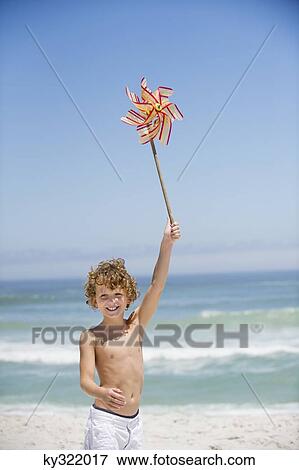 Portrait of a boy holding a pinwheel on the beach View Large Photo Image Stock Photo - Portrait of a boy holding a pinwheel on the beach. Fotosearch