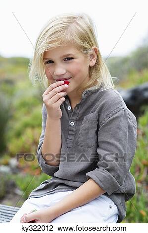 Stock Image - Portrait of a girl eating fruit. Fotosearch