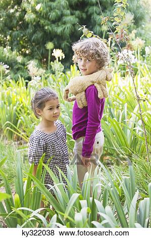 Portrait of a smiling boy standing with little girl in a garden View Large Photo Image Stock Photo - Portrait of a smiling boy standing with little girl in a garden. Fotosearch