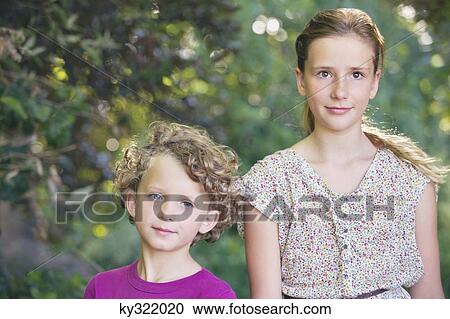 Stock Image - Portrait of cute little siblings walking together in a garden. Fotosearch