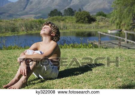 Shirtless little boy sitting with his eyes closed against mountain View Large Photo Image Stock Photo - Shirtless little boy sitting with his eyes closed against mountain. Fotosearch