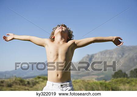 Shirtless little boy standing with his eyes closed and arms outstretched against mountain View Large Photo Image Stock Photo - Shirtless little boy standing with his eyes closed and arms outstretched against mountain. Fotosearch