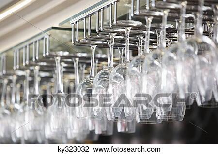 Stock Image - Wine glasses arranged in wine glass stand in a bar. Fotosearch
