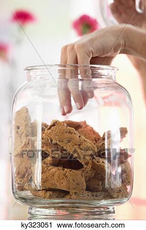 Stock Image - Woman taking out cookies from a jar in a restaurant. Fotosearch