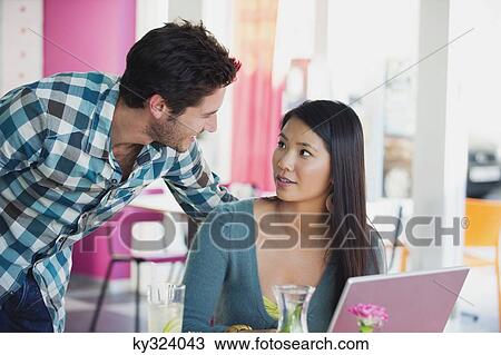 Friends looking at each other while using a laptop in a restaurant View Large Photo Image Stock Image - Friends looking at each other while using a laptop in a restaurant. Fotosearch