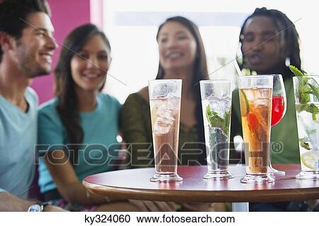Friends sitting in a restaurant with focus on beverage View Large Photo Image Stock Image - Friends sitting in a restaurant with focus on beverage. Fotosearch