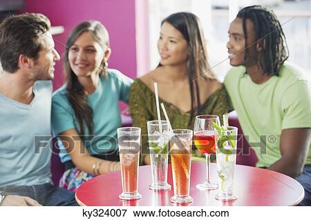 Friends sitting in a restaurant with focus on beverage View Large Photo Image Stock Photo - Friends sitting in a restaurant with focus on beverage. Fotosearch
