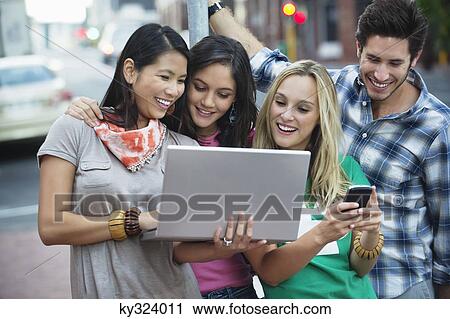 Friends using electronic gadgets outdoors View Large Photo Image Stock Image - Friends using electronic gadgets outdoors. Fotosearch