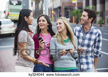 Picture - Friends using mobile phones outdoors. Fotosearch