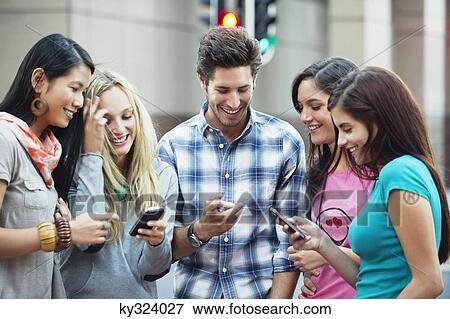 Friends using mobile phones outdoors View Large Photo Image Stock Photo - Friends using mobile phones outdoors. Fotosearch
