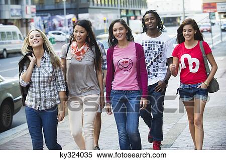 Friends walking on the sidewalk against cars View Large Photo Image Stock Photography - Friends walking on the sidewalk against cars. Fotosearch
