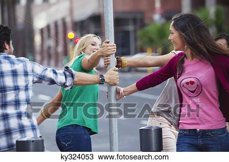Group of young friends swinging around pole View Large Photo Image Stock Image - Group of young friends swinging around pole. Fotosearch