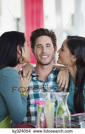 Man being kissed by two women in a restaurant View Large Photo Image Picture - Man being kissed by two women in a restaurant. Fotosearch