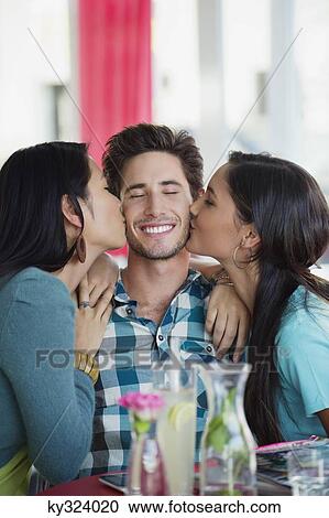 Man being kissed by two women in a restaurant View Large Photo Image Stock Image - Man being kissed by two women in a restaurant. Fotosearch