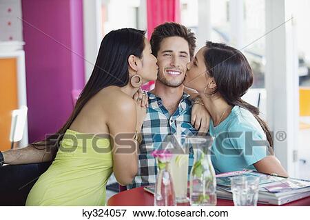 Stock Photo - Man being kissed by two women in a restaurant. Fotosearch