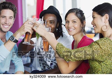 Portrait of friends toasting drinks in a restaurant View Large Photo Image Stock Photo - Portrait of friends toasting drinks in a restaurant. Fotosearch