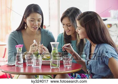 Stock Photo - Three women eating food in a restaurant. Fotosearch