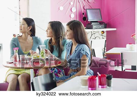 Three women looking away while eating food in a restaurant View Large Photo Image Stock Image - Three women looking away while eating food in a restaurant. Fotosearch