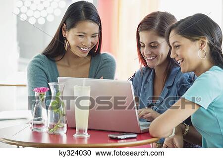 Stock Image - Three women using laptop in a restaurant. Fotosearch
