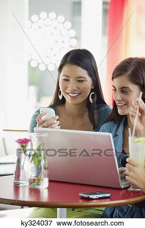 Three women using laptop in a restaurant View Large Photo Image Stock Photo - Three women using laptop in a restaurant. Fotosearch