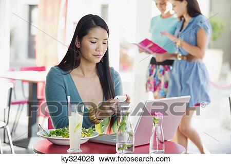 Woman reading text message while eating food in a restaurant View Large Photo Image Stock Photo - Woman reading text message while eating food in a restaurant. Fotosearch
