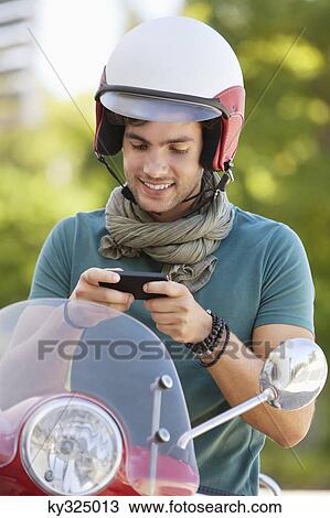 Man sitting on a scooter and text messaging View Large Photo Image Stock Image - Man sitting on a scooter and text messaging. Fotosearch