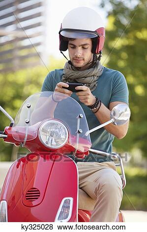 Man sitting on a scooter and text messaging View Large Photo Image Stock Photo - Man sitting on a scooter and text messaging. Fotosearch