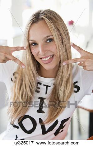 Portrait of a beautiful woman showing peace sign at a cafe View Large Photo Image Stock Photo - Portrait of a beautiful woman showing peace sign at a cafe. Fotosearch