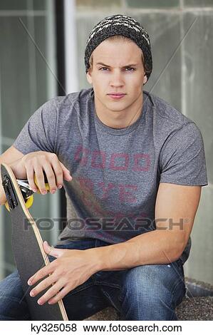 Portrait of a man holding skateboard View Large Photo Image Stock Photo - Portrait of a man holding skateboard. Fotosearch