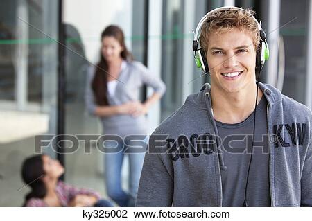 Portrait of a man listening to music with headphones in a campus View Large Photo Image Stock Image - Portrait of a man listening to music with headphones in a campus. Fotosearch