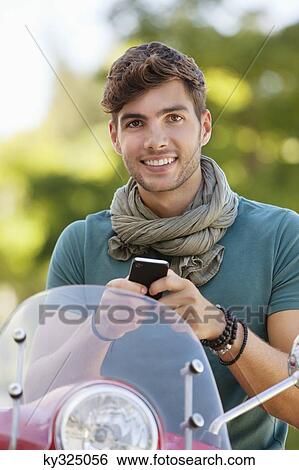 Portrait of a man sitting on a scooter and text messaging View Large Photo Image Stock Photograph - Portrait of a man sitting on a scooter and text messaging. Fotosearch