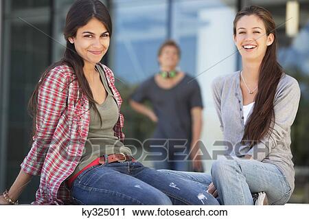 Stock Image - Portrait of two female friends sitting in a campus. Fotosearch