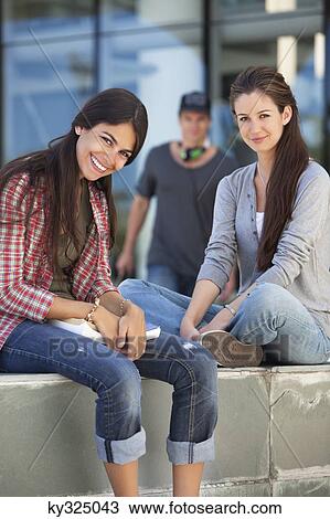 Portrait of two female friends sitting in a campus View Large Photo Image Stock Image - Portrait of two female friends sitting in a campus. Fotosearch
