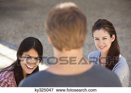 Portrait of two women smiling with a man standing in front of them View Large Photo Image Stock Photo - Portrait of two women smiling with a man standing in front of them. Fotosearch