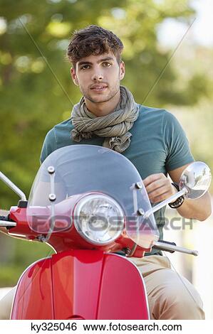 Portrait of young man sitting on scooter View Large Photo Image Stock Photograph - Portrait of young man sitting on scooter. Fotosearch